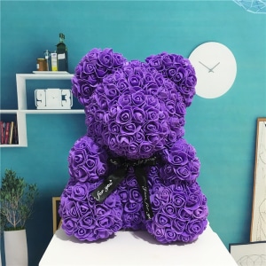 Peluche orso fiore viola seduto davanti a una parete blu con un reloge