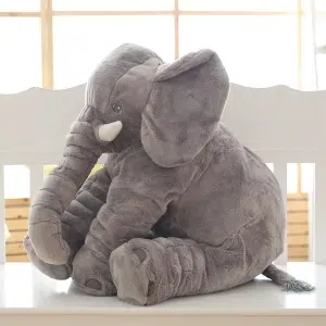 Peluche di un elefante grigio seduto. Ha grandi orecchie e zanne. Il peluche di cotone è morbido.