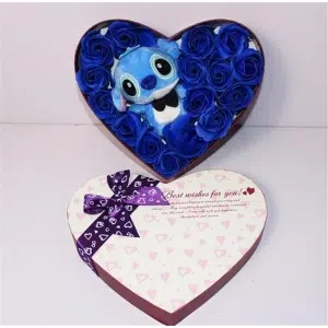 Il peluche blu di Stich è contenuto in una scatola a forma di cuore. Ci sono rose blu intorno a lui. Sul coperchio della scatola, c'è un nastro viola con iscrizioni e motivi a cuore. Stich indossa un papillon nero.