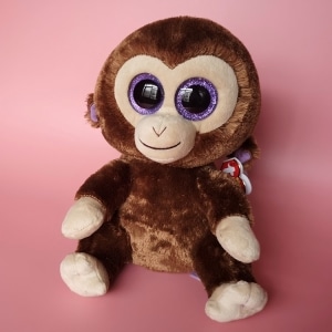 Piccola scimmia marrone in peluche su sfondo rosa