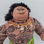 peluche del personaggio Moana Maui dal cartone animato Disney, vediamo la sua testa e il suo busto interamente tatuati