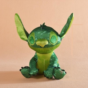 Stitch, l'eroe dei cartoni animati Disney, è un peluche verde scuro, con orecchie e pancia verde chiaro, seduto con le orecchie alzate